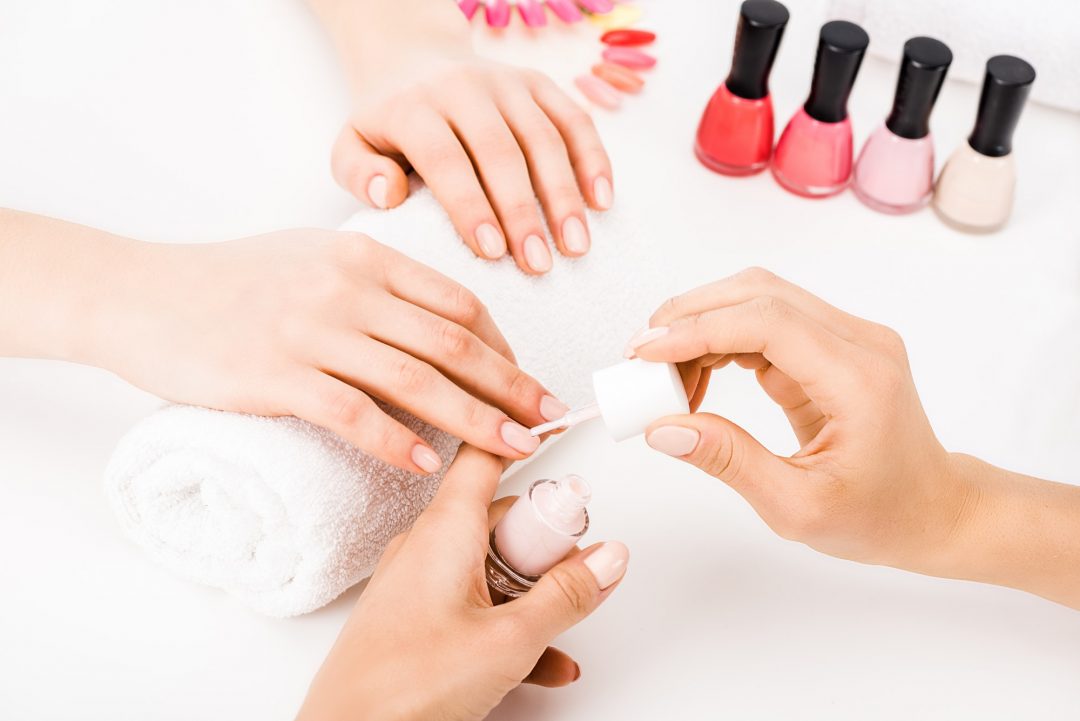 Inicio 1 girl holding hands on towel while manicurist applying nail polish